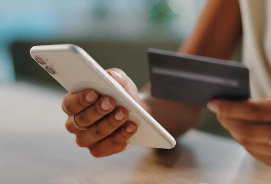 Credit card, phone and hands of person in home for online shopping, internet purchase and payment. Ecommerce, fintech and woman on smartphone typing password for website sale, savings and banking